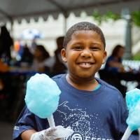 A cute kid in a gvsu laker effect T-shirt is helping serve cotton candy to the people at the party